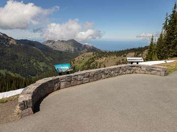 A stone wall with signage at a mountain overlook.