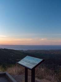 A wayside sign near an overlook view of a valley/