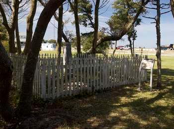 White picket fence surrounds the small family cemetery under the shade trees.