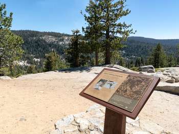 A wayside exhibit stands at a scenic roadside pullout that overlooks the high country landscape.