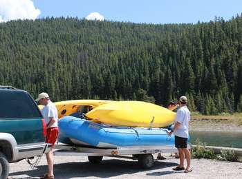 Visitors unloading three boats, two yellow canoes and one blue raft, from a trailer from the river access downstream from the Jackson Lake Dam.