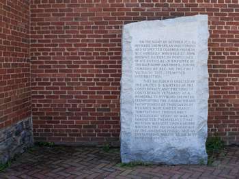 Large stone memorial in front of brick wall.