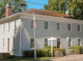 Restored large home of John McLoughlin, with grey siding, white trim, and a brown roof
