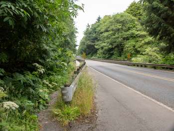 A trail runs just on the other side of a highway guardrail.