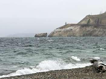 Choppy water of a large lake with a beach of worn rocks