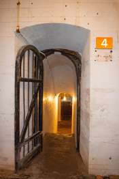 White brick interior fort wall and arch. A brown metal sign with the number,