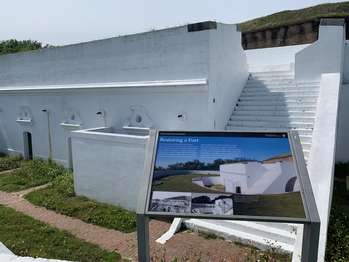 National Park Service sign in front of the white walls of the Spanish Water Battery.