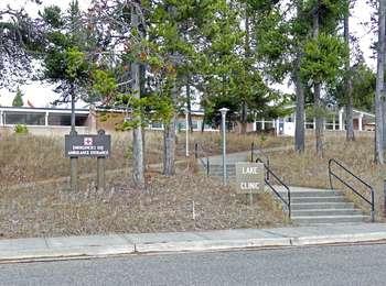 A sidewalk and stairs leads up a hill to a one-story building surrounded by trees