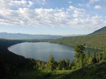 View from Phelps Lake Overlook with oval lake surrounded by a glacial moraine covered in conifers.