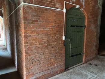 Large green wooden door in a brick fort wall.