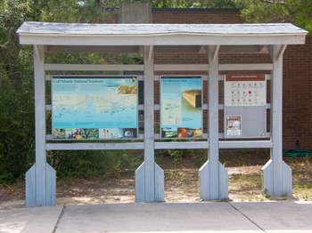A wooden orientation kiosk with information panels and a bulletin board.