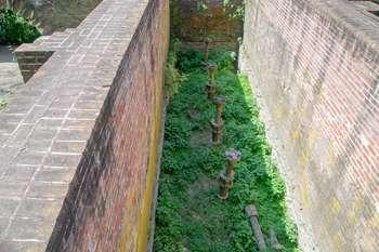  Old turbine ruins in between two brick walls.