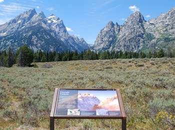 Cascade Canyon wayside sign in sagebrush with Cascade Canyon to the west. Cathedral Group peaks to the south and Mt. St. John to the north.