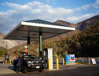 A person cleans his vehicle's windshield at a gas pump.