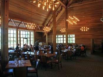 Geometric lights glow above dining tables in a wood-paneled room with square windows