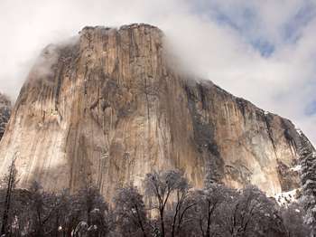 Clouds surround a large granite monolith. 