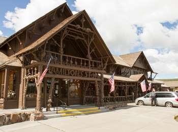 Large brown building with peaked roof above each entrance and ornate log porch supports.
