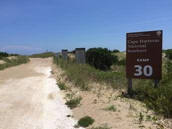 Off-road vehicle ramp leading to the beach, with brown signs to the right.