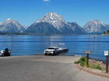 White truck with trailer backing a power boat down the Signal Mountain boat launch into Jackson Lake.