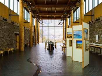 Interior of a museum with displays and large windows looking outside at the natural landscape