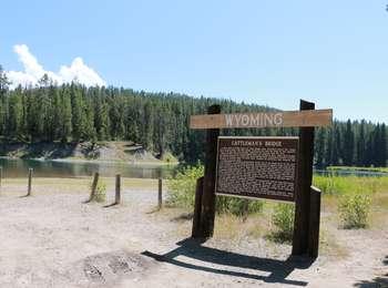 Wooden sign at Cattlemans Bridge access with sandy beach leading to Snake River channel.