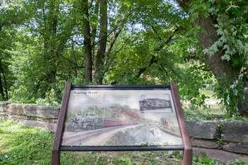  Wayside in front of trees and small stone wall.
