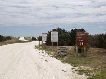 Shell-covered vehicle ramp leading out to the beach, with the brown entrance sign to the right.