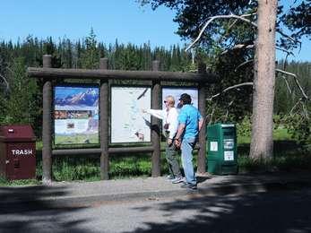 Visitors at the North John D. Rockefeller, Jr. Memorial Parkway turnout with wayside, trash receptacle, and newspaper dispenser.