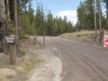 A gravel service road leads off to the trailhead.
