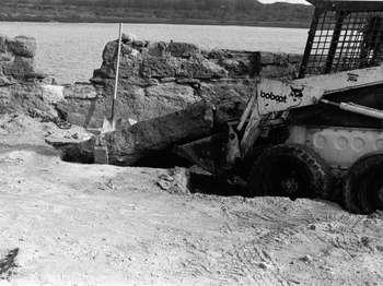 A Bobcat tractor digs into the gundeck of the fort.