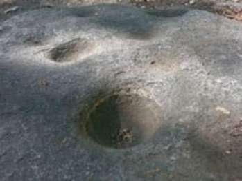 Sunlight hits bowl-shaped depressions that were pounded into granite rock.