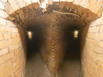 Two long, narrow, and brick tunnels extend back to a light at the end of each tunnel.
