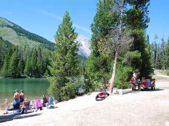 Visitors at String Lake with chairs set up on the shore looking north toward Mount Moran.