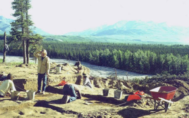 Archaeologists excavate on a hill near a river 
