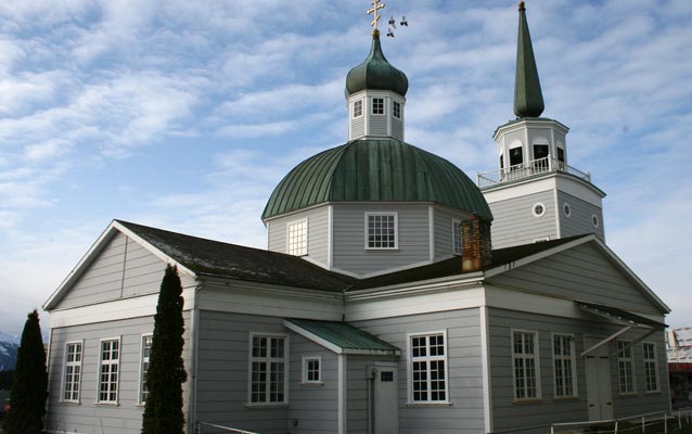 A grey cathedral with a green roof and white trim