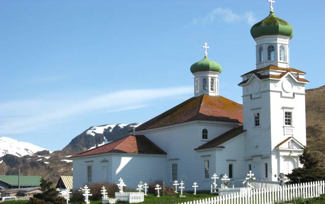 A white Russian Orthodox Church with a red roof and green onion domes. A white Russian Orthodox Church with a red roof and green onion domes.