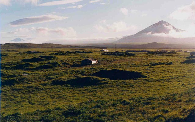 Building sits in valley with mountain in background Building sits in valley with mountain in background