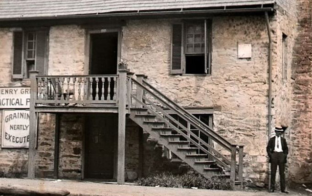 A man stands in front of the Old Stone House circa 1900.