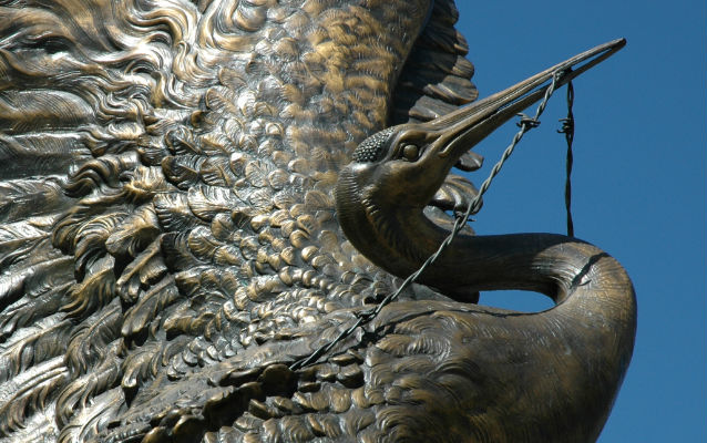 Bronze sculpture of a crane with barbed wire in its bill. Bronze sculpture of a crane with barbed wire in its bill.