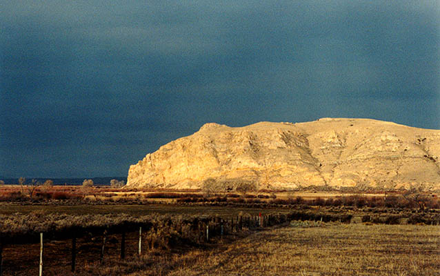 Rock formation lit by sunlight with dark storm clouds behind. Rock formation lit by sunlight with dark storm clouds behind.