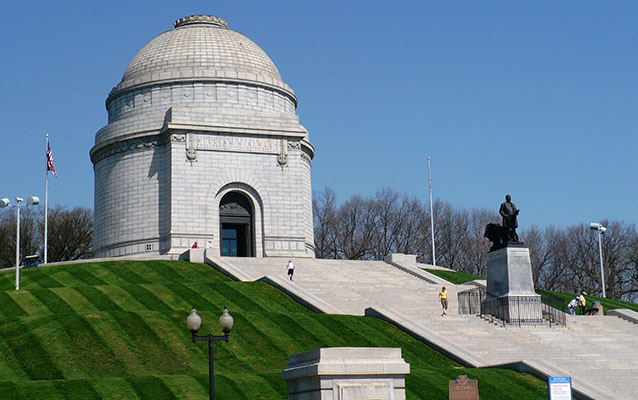 Large circular, domed marble building surrounded by green lawn.
