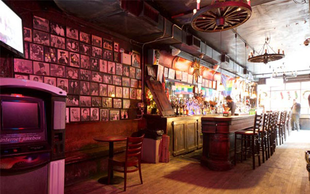 Interior view of Julius Bar. Bar with stools; several images on the wall. 