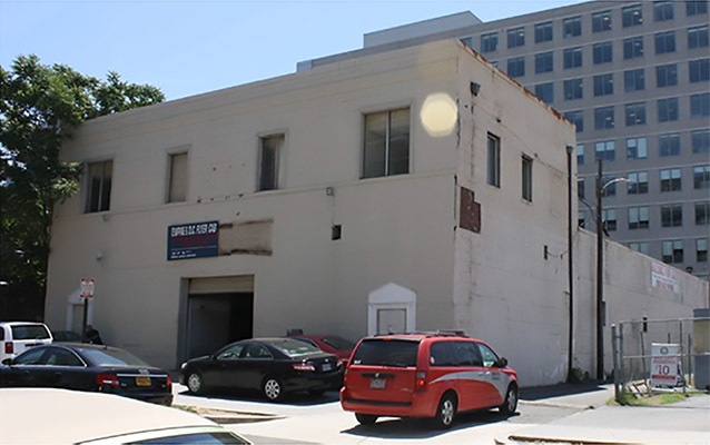 Two story building, painted white. Cars parked out front.