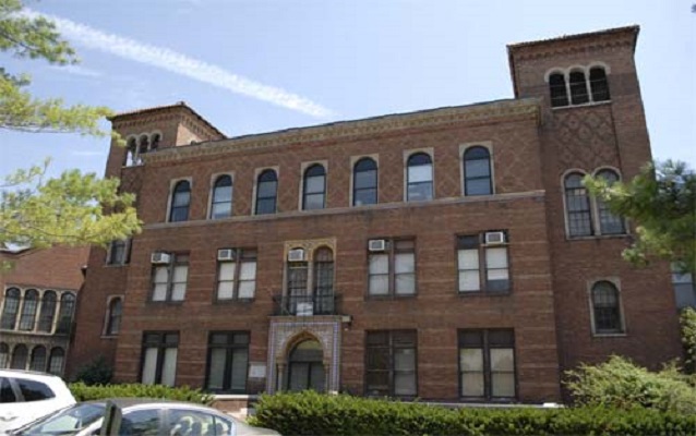 Red brick building with gothic door arch and towers on either side.