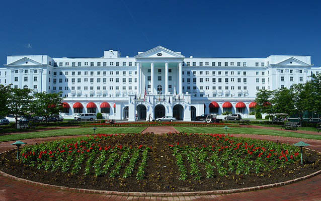 Exterior view of a large white building with garden in the foreground.