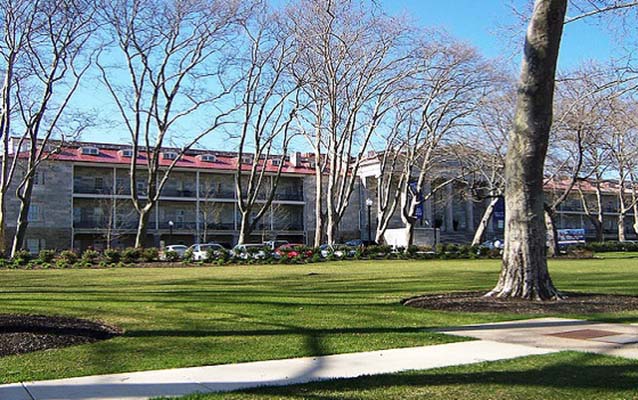 Exterior view of a three story structure with trees in front.