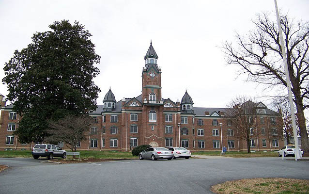 Exterior of a large, brick institutional building with clock tower.