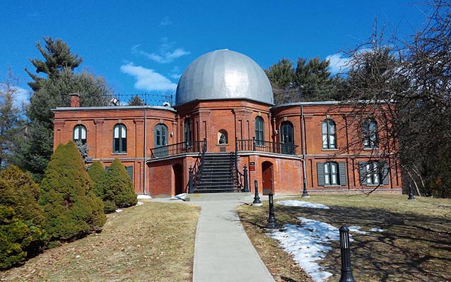 The outside of the brick observatory building with shiny metal dome