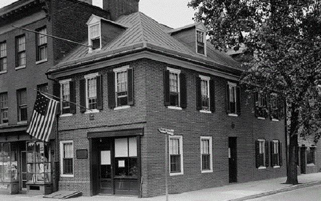 Photograph of front and side of Flag House with American flag hanging out front. Photograph of front and side of Flag House with American flag hanging out front.