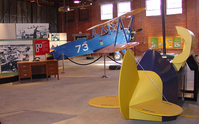 A blue airplane sits in the background with a yellow mock airplane in front